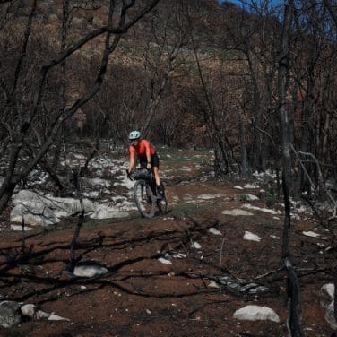 cyclist doing bikepacking and descending a mountain trail