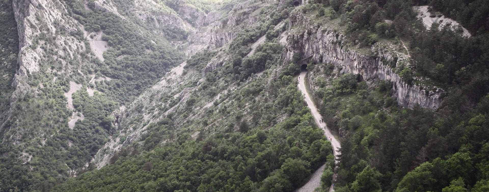 mountains landscape with road through a valley and pedaling cyclists