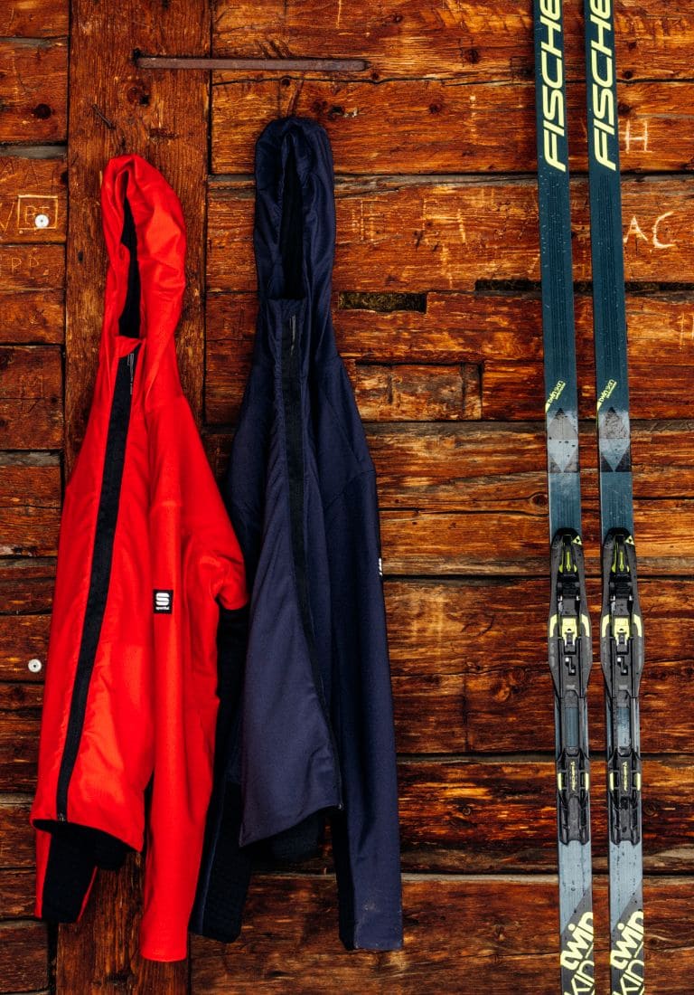 hanging ski clothes and a pair of cross-country skis leaning on the wall hanging ski clothes and a pair of cross-country skis leaning on the wall